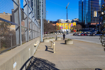 an African American teenager in a black and red sweat suit walking along the sidewalk with cars driving, a colorful mural and buildings and skyscrapers in the cityscape in downtown Atlanta Georgia USA © Marcus Jones