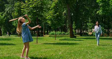 Cheerful girl playing badminton with mother in park. Active family rest concept.