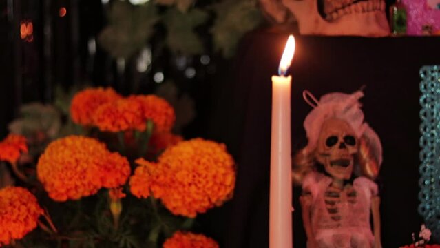 Vela larga encendida chorrea sobre una botella en ofrenda de d&iacute;a de muertos