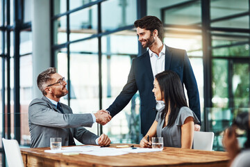 We look forward to having you with us. Shot of businessmen shaking hands during a meeting in a modern office.