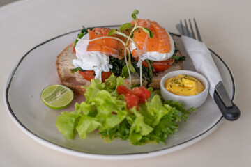 Toast with poached eggs, tomato and salmon on plate in cafe, breakfast time