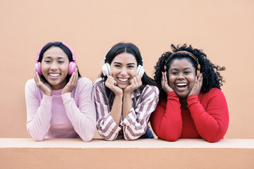 Young multiracial women smiling on camera while listening music playlist with wireless headphone