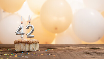 Happy birthday card with candle number 42 in a cupcake against the background of balloons. Copy...