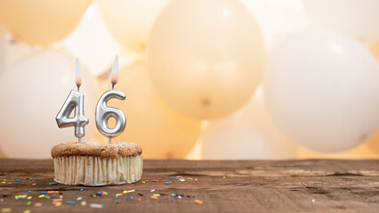 Happy birthday card with candle number 46 in a cupcake against the background of balloons. Copy space happy birthday for forty six years old
