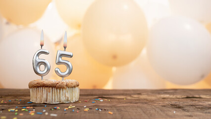 Happy birthday card with candle number 65 in a cupcake against the background of balloons. Copy...
