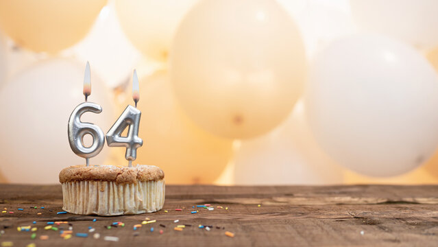 Happy birthday card with candle number 64 in a cupcake against the background of balloons. Copy space happy birthday for sixty four years old
