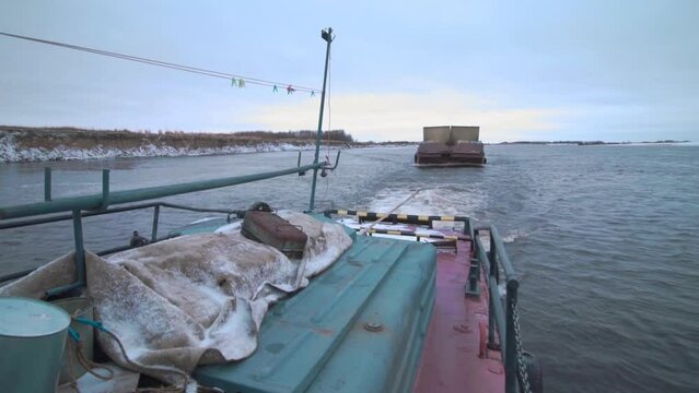 View from the ship on a barge trailer with goods. Clip. Concept of water transportation, containers on a barge and a wide river.
