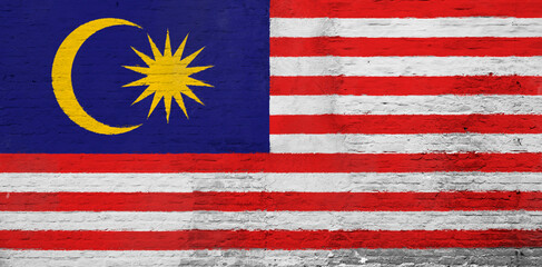 Full frame photo of a weathered flag of Malaysia painted on a plastered brick wall.