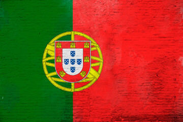 Full frame photo of a weathered flag of Portugal painted on a plastered brick wall.