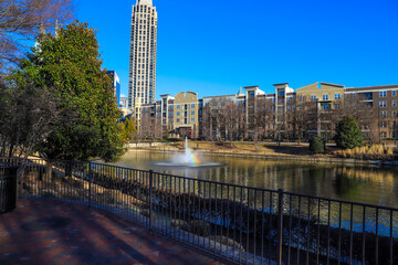 skyscrapers and office buildings in the city skyline with a rippling green lake surrounded by...