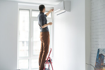 Fototapeta na wymiar Professional technician maintaining modern air conditioner indoors