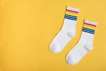 white cotton socks with rainbow colors on yellow background, LGBTQ symbol, gift idea