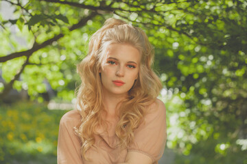 Cute blonde woman on green leaves background