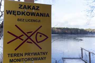 Tabliczka informacyjna o zakazie wędkowania na jeziorze bez wykupienia odpowiedniej licencji - obrazy, fototapety, plakaty