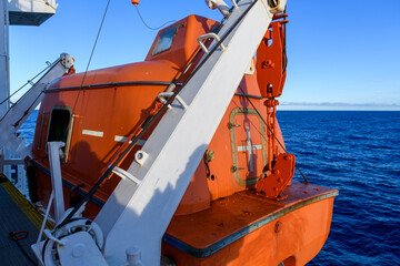 Lowering orange totally enclosed lifeboat to water. Abandon ship drill. Lifeboat training. Man over...