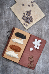 Notebook for recipes with cooking ingredients: sugar, cacao, flour of wheat and coconut on a gray grunge background. Selective focus