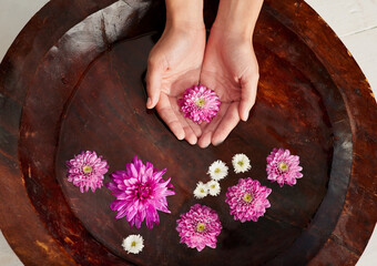Soaking up at the spa. Cropped shot of a womans hands in a flower filled water bowl at a spa.