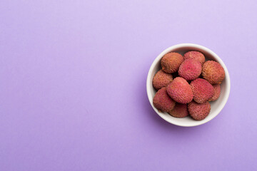Lychee fruit in bowl on color background. Top view, copy space text