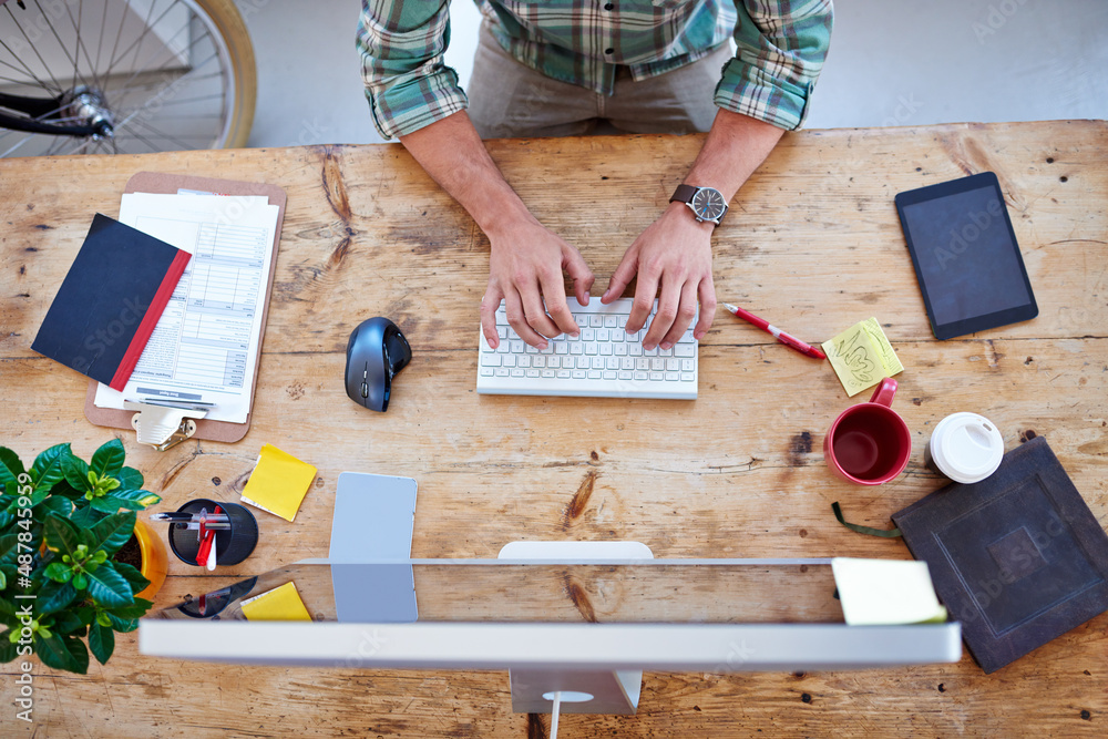 Poster creative professional at work. overhead shot of a creative professionals desk while he is typing on 