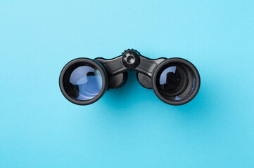 Black binoculars on color background. Top view - Powered by Adobe