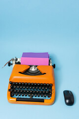 Typewriter and computer mouse on blue background