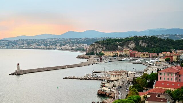 View of the Mediterranean sea coast in Nice, hills with greenery, residential buildings, yachts, France
