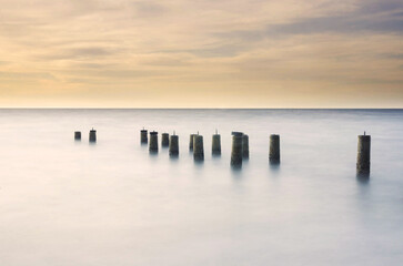 Fototapeta premium Scenery of a beautiful sunset with a pillars of jetty left over