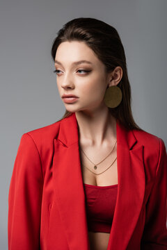 stylish young woman in red blazer looking away isolated on grey.