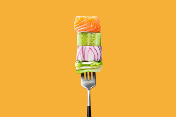 Close-up of fork with food on it: delicious fillet salmon, cucumber, onion, green salad on orange background. Concept of healthy diet and clean eating, balanced nutrition space for text - obrazy, fototapety, plakaty