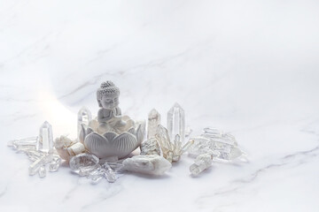 Clear quartz minerals and little Buddha statue on light marble background. gemstones crystals for healing esoteric ritual, spiritual Magic practice, relaxation and meditation. life balance concept