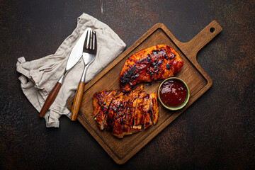 Grilled turkey or chicken marinated fillet with red sauce served and sliced on wooden cutting board...