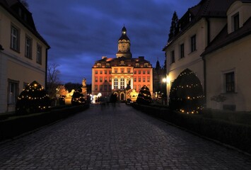 Książ Castle illuminated at dusk seen from the entrance