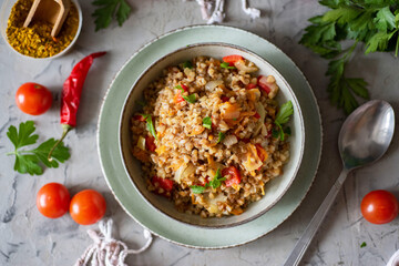 Vegetarian food for the whole family: stewed buckwheat porridge with vegetables and fresh herbs in...