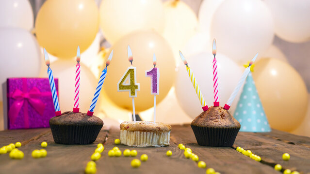 A beautiful birthday card for a girl with the number 41 in a cupcake against the background of balloons. Congratulations on the birthday of forty-one years for a girl, a gift box