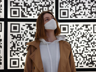 woman in a white protective mask against the background of large qr codes - 487850969