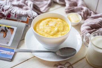 Healthy breakfast for the whole family: milk corn porridge in a white plate on a white table. close-up