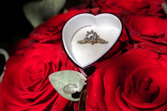 Wedding ring in a gift box in a bouquet of red roses, a gift for March 8