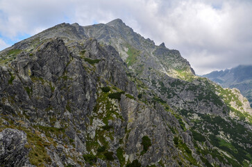 Fototapeta na wymiar View of sharp green mountain and rock landscape with low clouds over the peaks in High Tatras, Slovakia