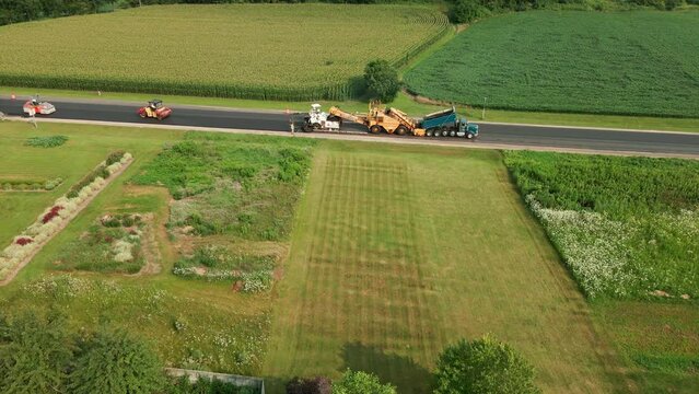 Bird view of rural highway being repaved on a beautiful summer day.  Heavy road equipment working down the highway. 