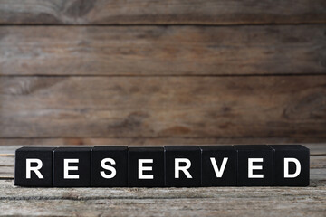 Word RESERVED made with cubes on wooden surface. Table setting element