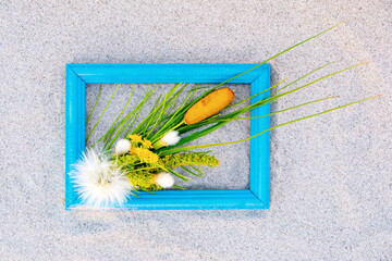 herbarium of wild flowers in a wooden frame on the sand