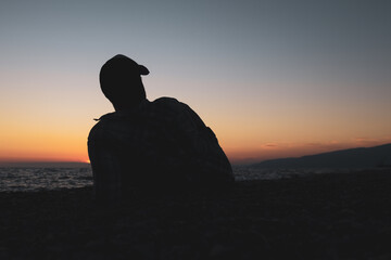 silhouette of a man lying on the seashore against the backdrop of the setting sun
