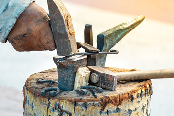 a blacksmith's hand with a hammer bends a nail on a small anvil