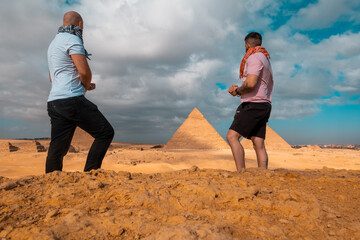 Two men travelers posing in front of the great pyramids of giza in cairo egypt. Traveling egypt...