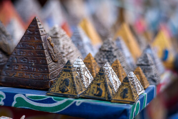 Many small colorful pyramid souvenirs for sale on the streets of cairo, egypt. Salesman looking to earn money and haggle with tourists, stone, limestone and alabaster figurines for sale - obrazy, fototapety, plakaty