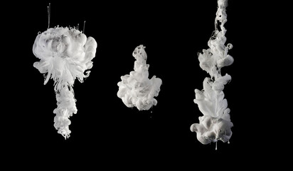  white Ink dropped into the water and photographed while in motion. Paint swirling in water. Grey cloud and smoke of paint in water isolated on black background.