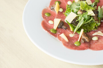 TTenderloin carpaccio with parmesan cheese and salad. Raw meat