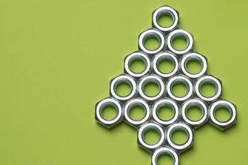 Metal nuts arranged in the shape of a triangle isolated on light green background with text space....