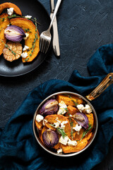 Pan with roasted pumpkin,onion,garlic,thyme and rosemary on dark blue background. Rustic food...