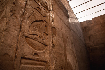 View of a hieroglyph symbol in the shape of a sailboat, seen on the ancient ruins in egypt. Light illuminating the area in the background